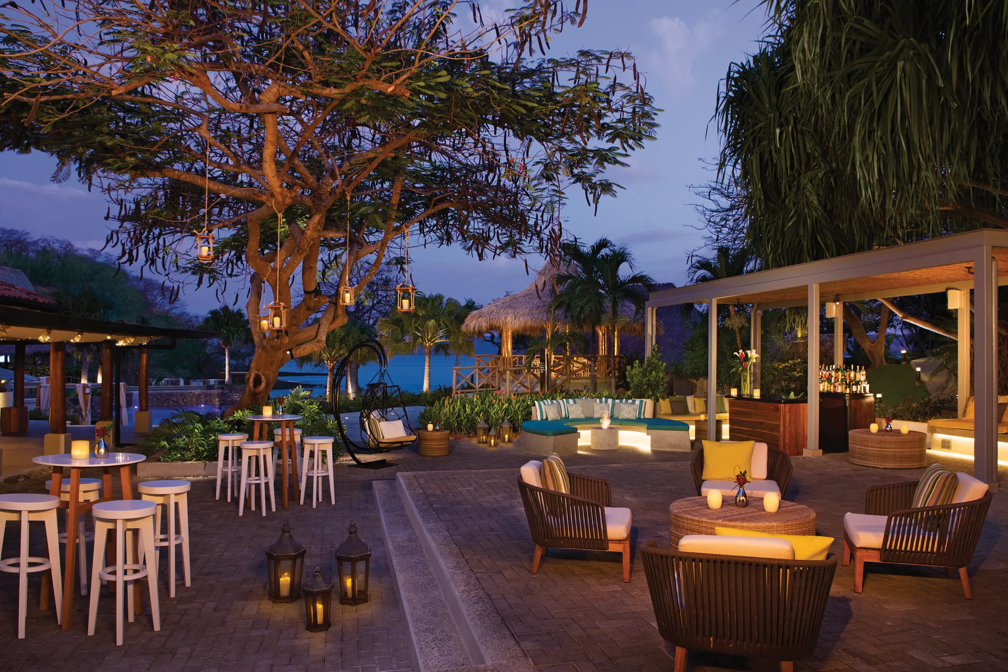 a patio with chairs and tables and a tree