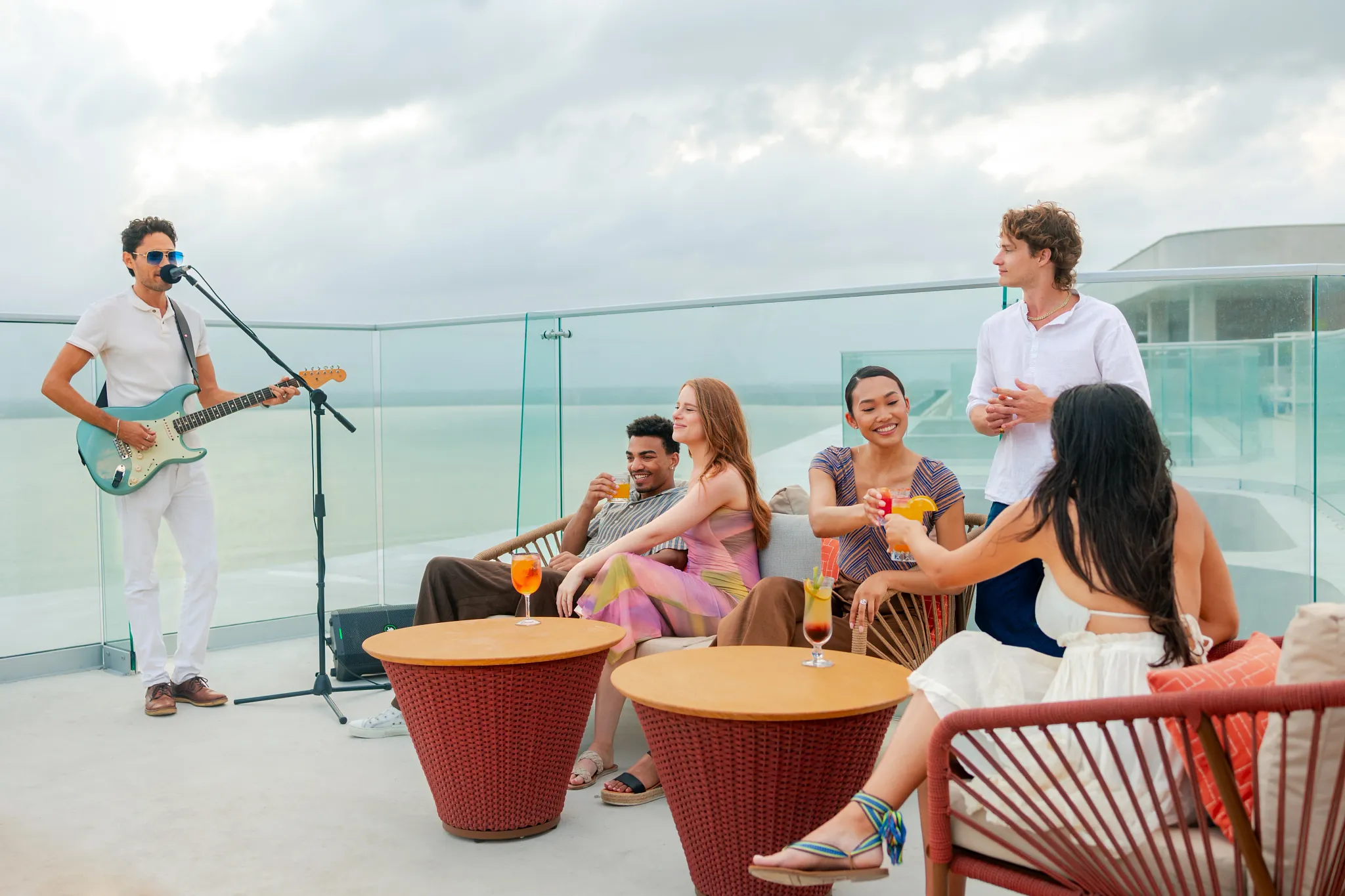 Friends being serenated by guitarist on rooftop