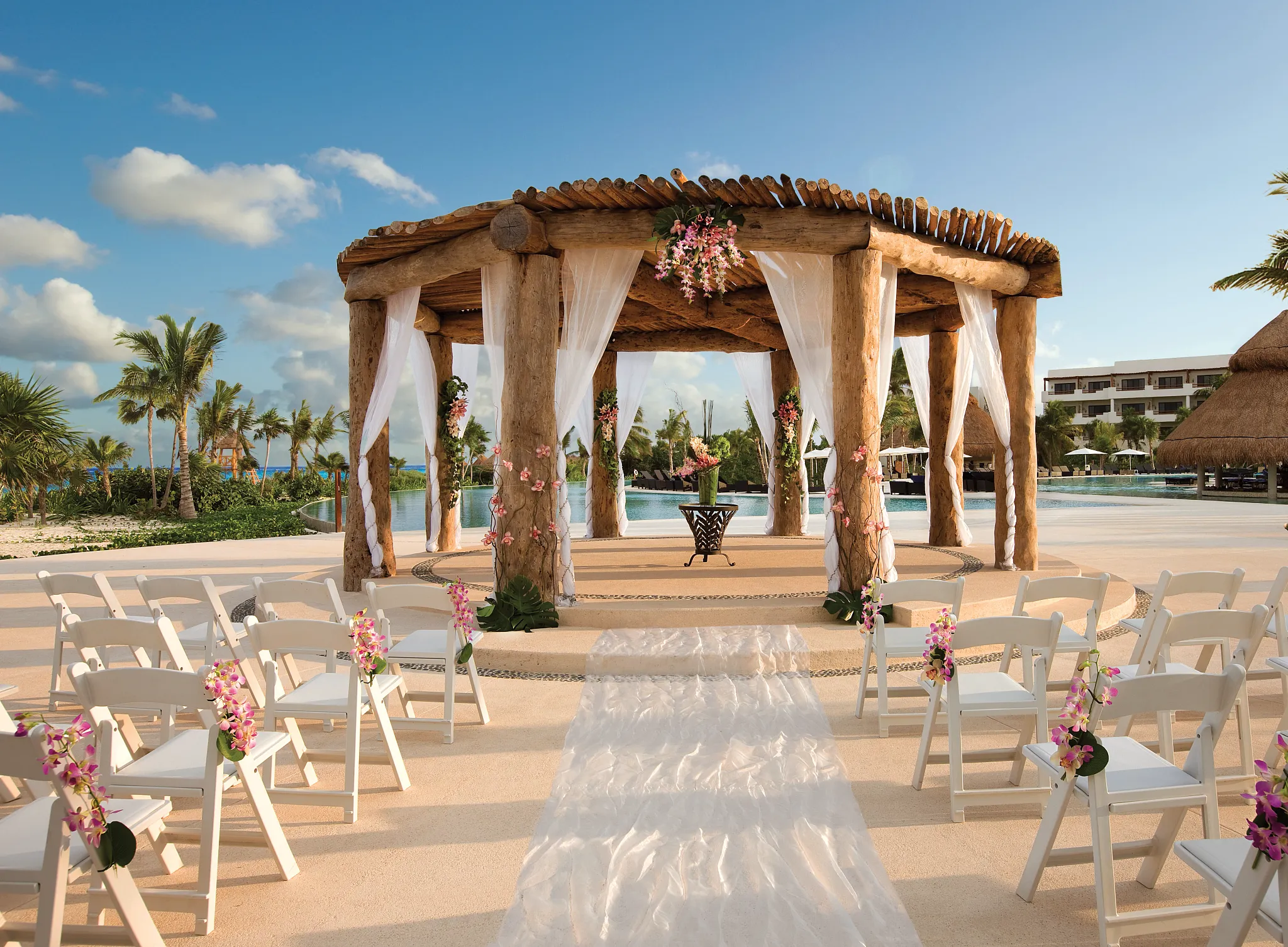 Oceanfront gazebo set up for a wedding with a white asile runner and flower arrangements