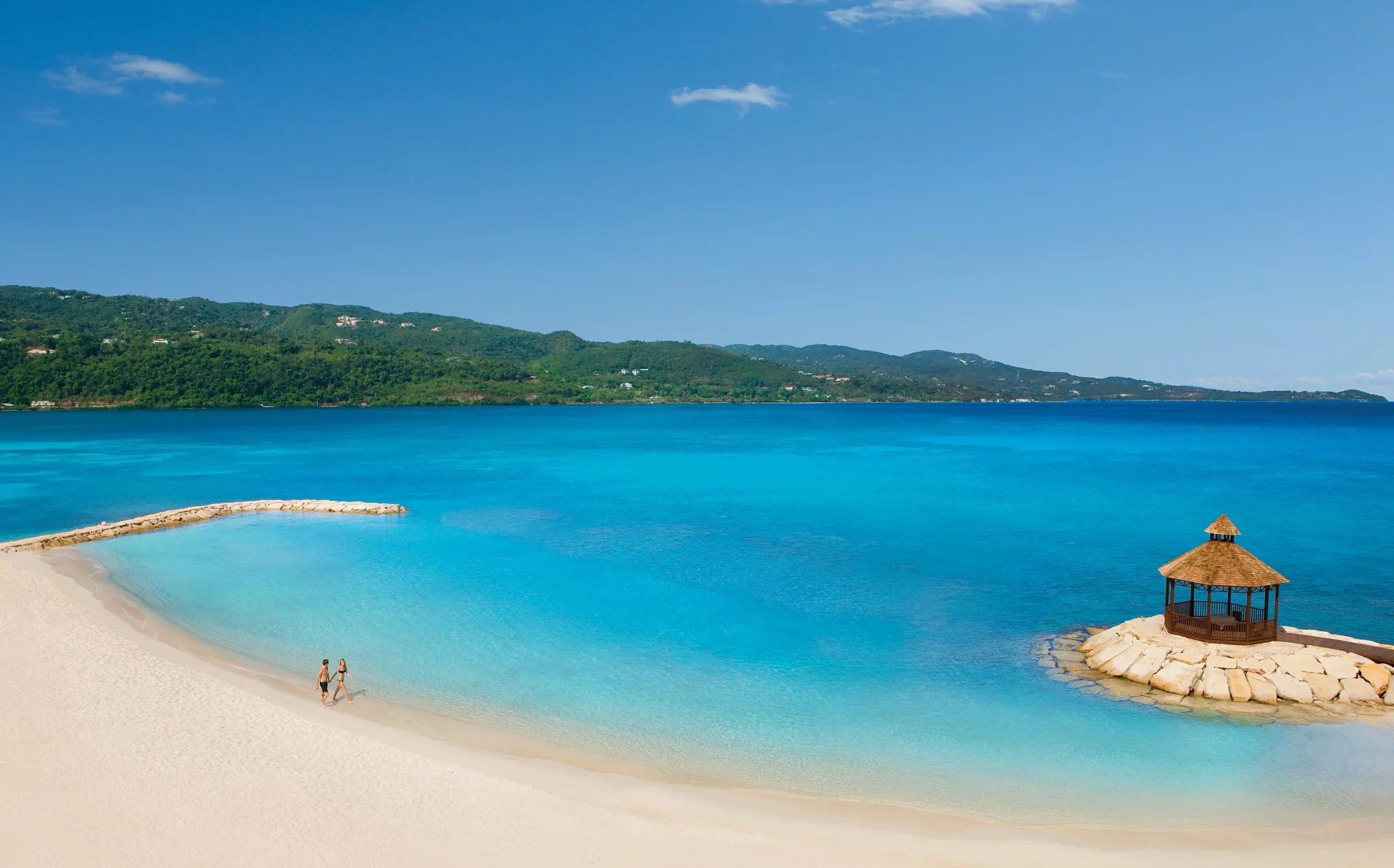 Aerial view of couple waking on the beach in jamaica