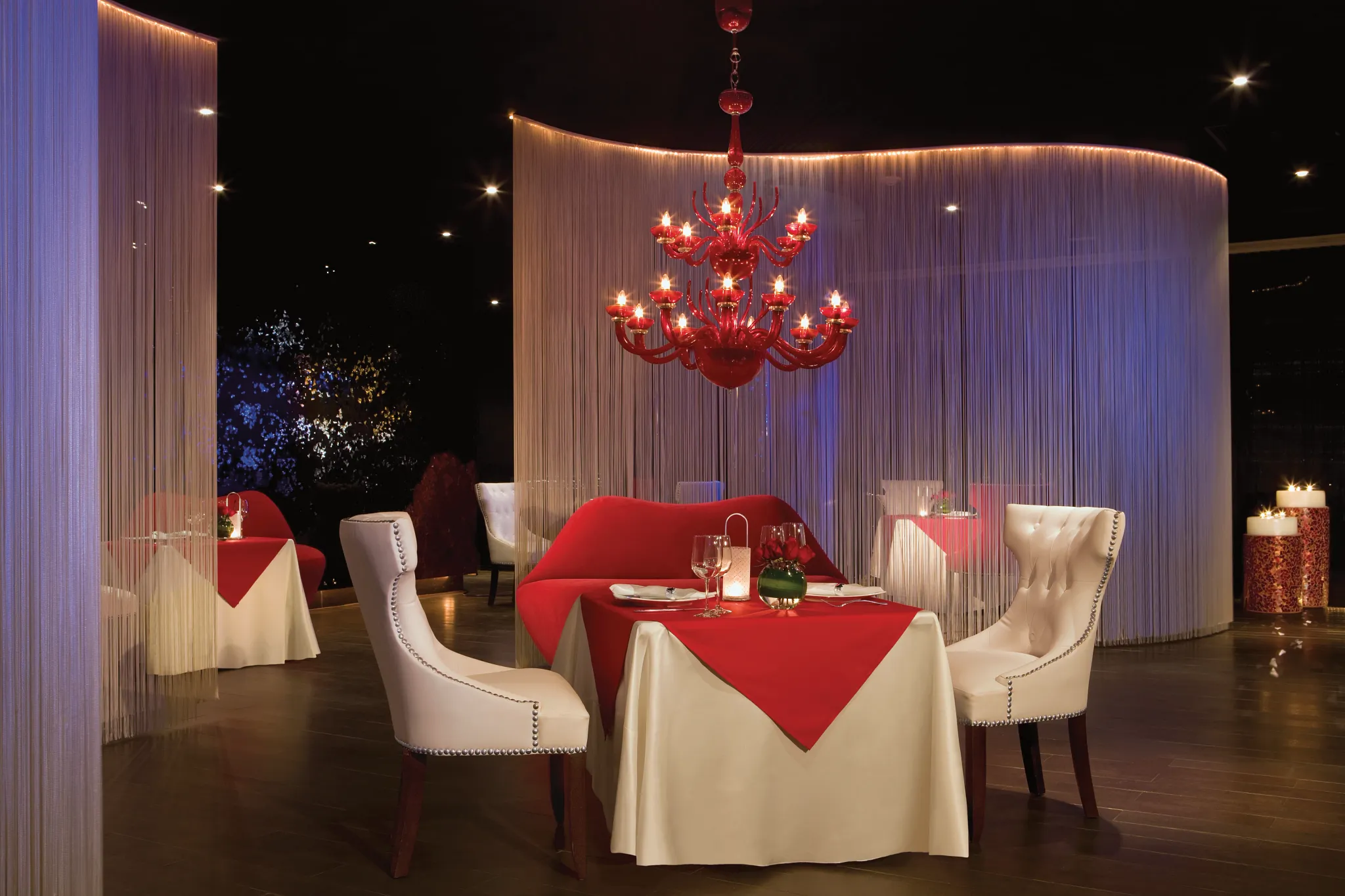 interior of a restaurant with red chandelier and table cloths