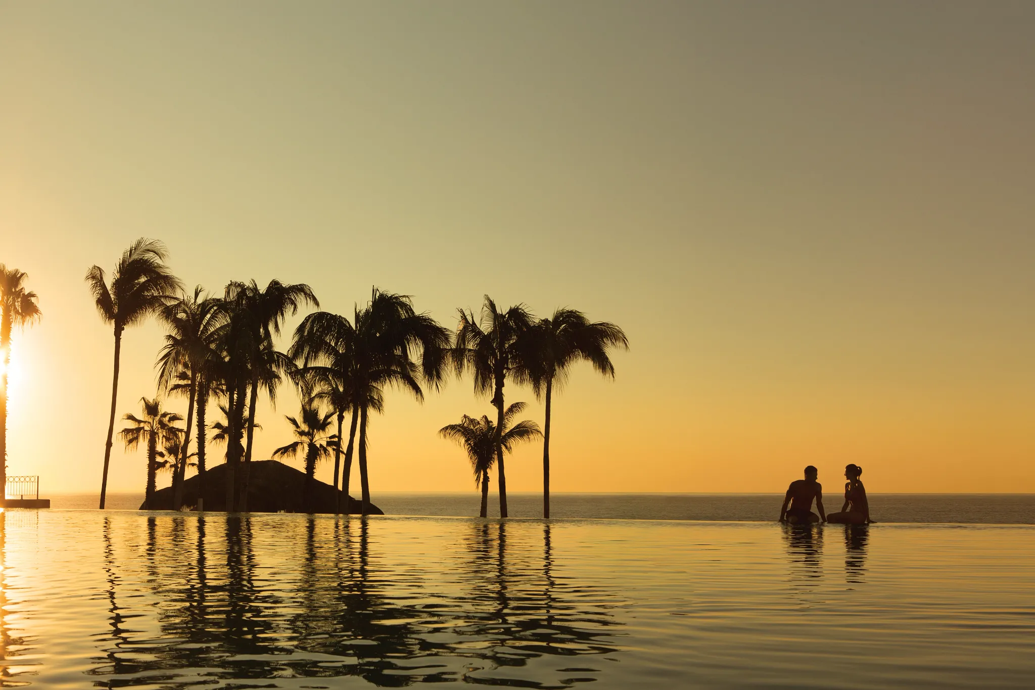 couple enjoying the sunset in an infinity pool