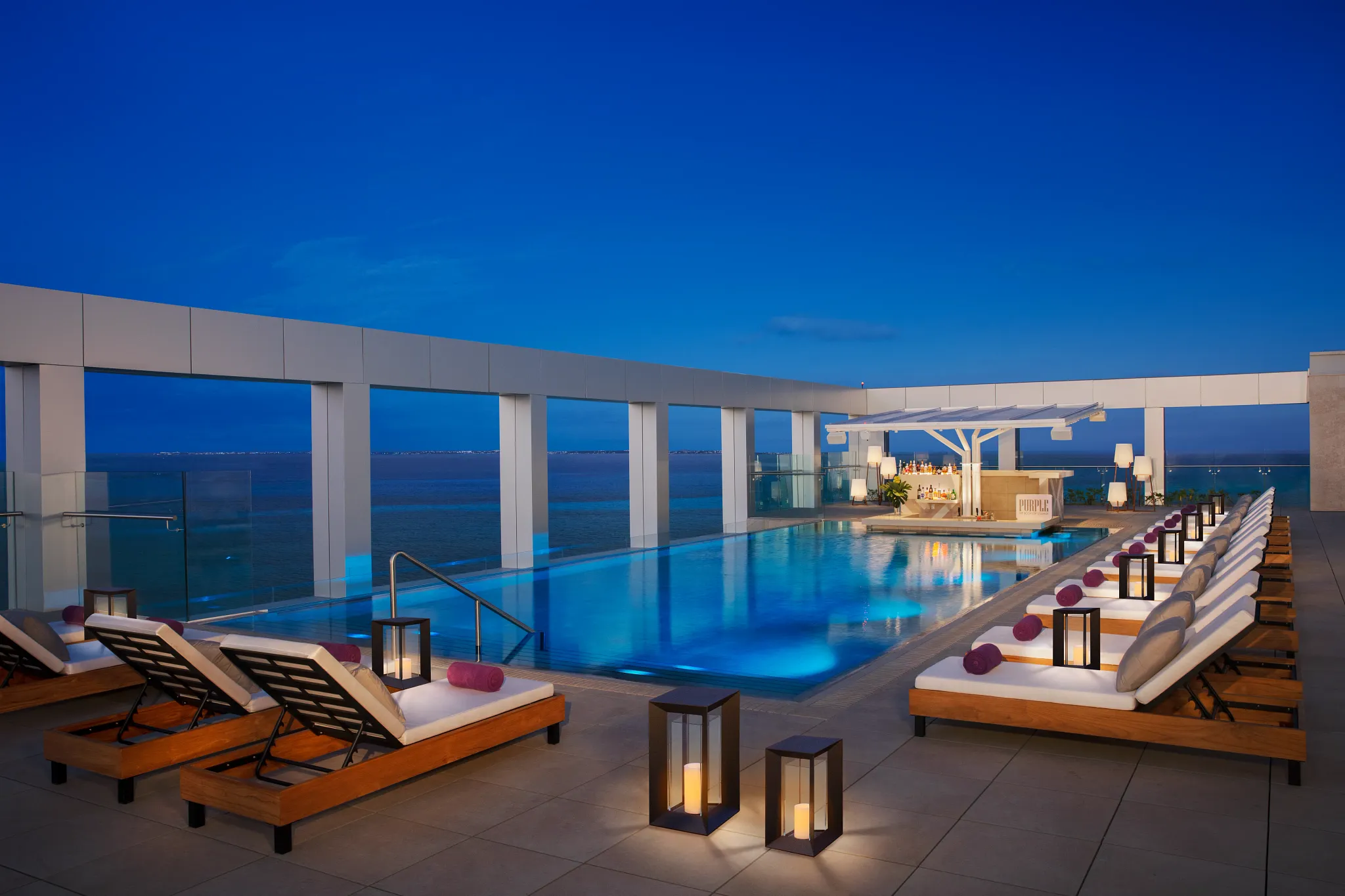 beautiful rooftop infinity pool with oceanfront views in a nighttime setting