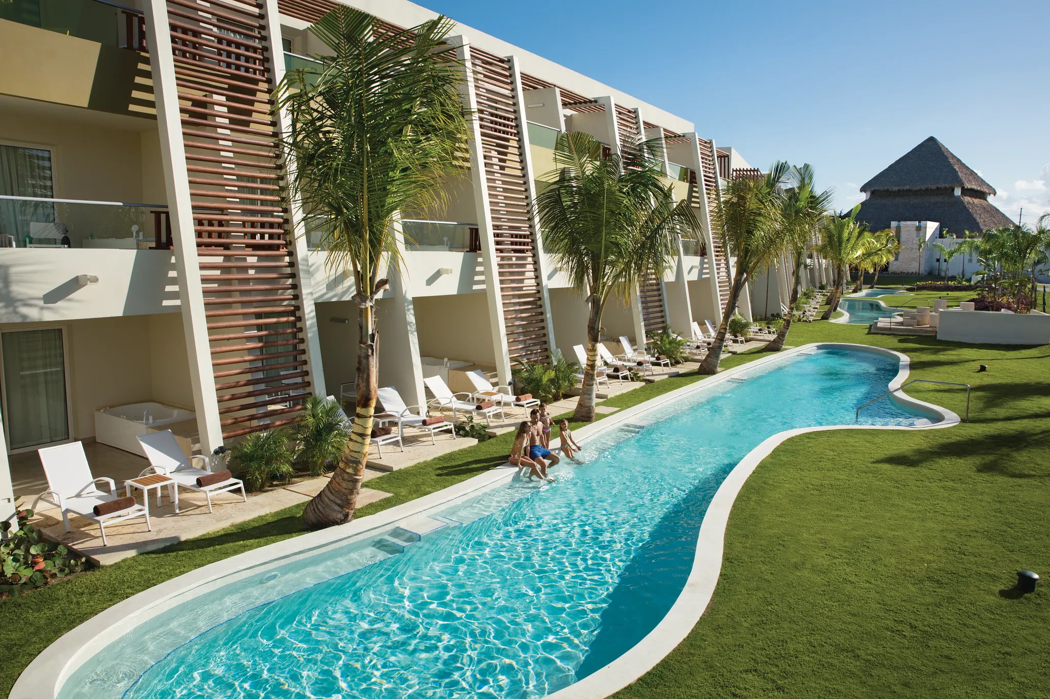 family sitting in front of a swim up pool by their hotel room