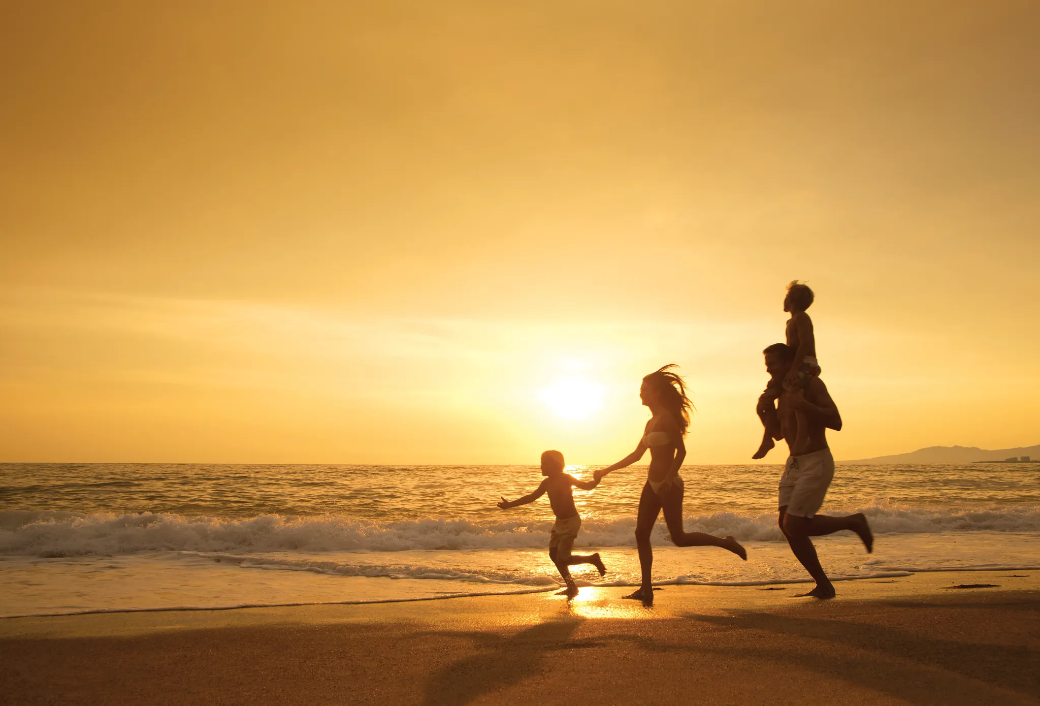 family running down the beach at sunset